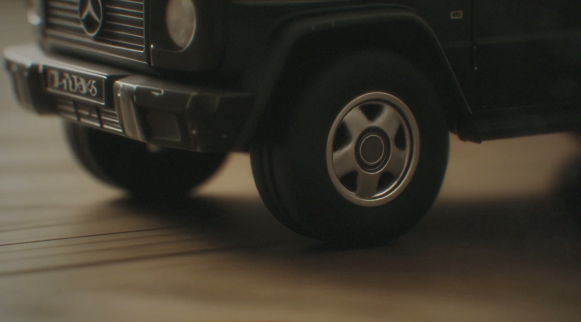Child's finger pushing miniature black G-Class toy forward