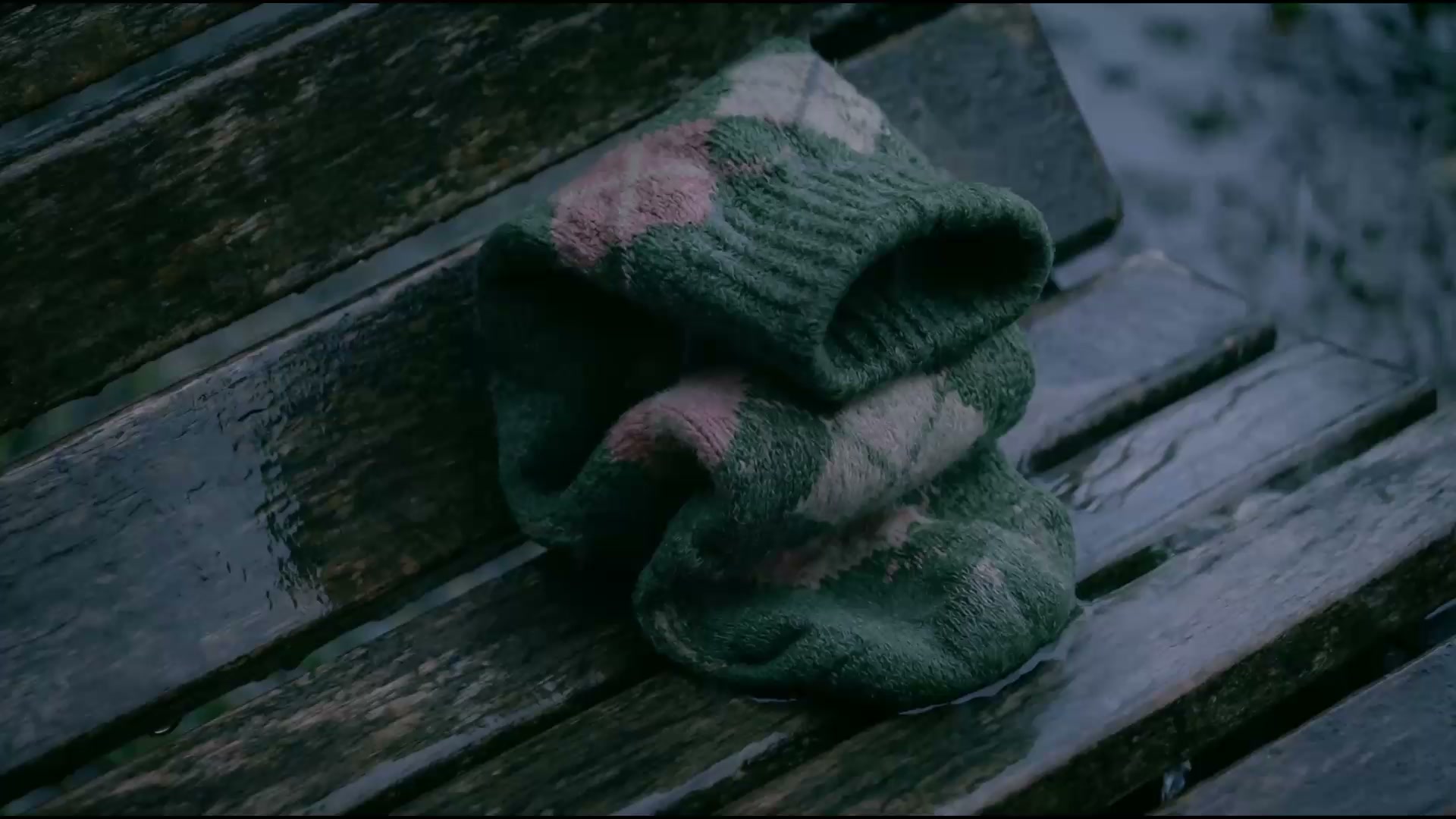 Wet sock resting on a park bench in the rain