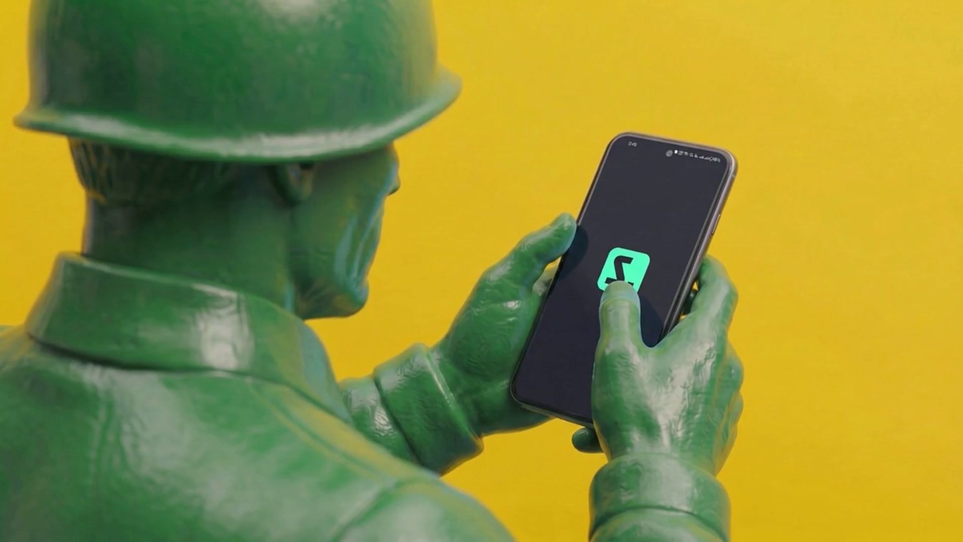 Toy soldier looking at a phone against yellow